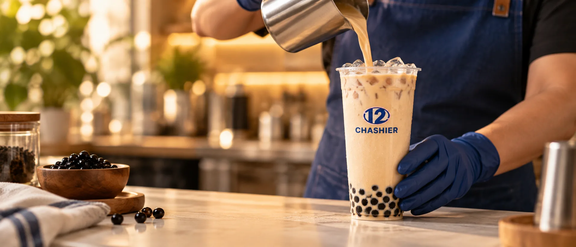 Bubble tea de Chashier preparándose en la barra: se vierte té con leche sobre el hielo de un vaso con perlas de tapioca.
